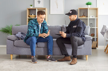 Policeman or detective interviews a male victim or witness of a home theft or burglary at the crime...