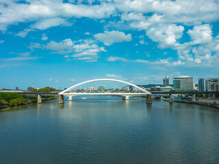 Fototapeta premium View of Merivale Bridge spanning the Brisbane River in Brisbane, Queensland, Australia. The bridge's white arches contrast with the blue sky and water. The city skyline is visible in the background.
