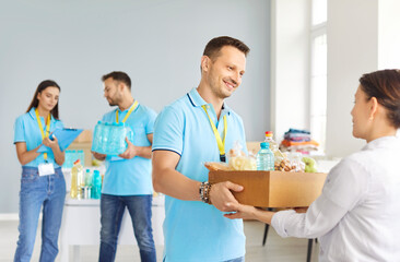 Portrait of a young cheerful male volunteer working at charity center giving free food donations in...