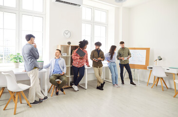 Fototapeta premium Diverse team of business people engages in a conversation during a meeting or training session in the office. Group focuses on teamwork, collaboration, and professional development in the workplace.