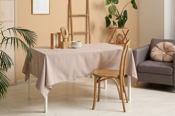 Dishes with decor on beige tablecloth in dining room interior