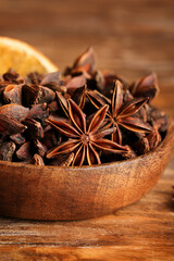 Bowl with anise stars on wooden background, closeup
