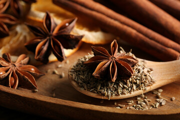 Anise stars with seeds and cinnamon in wooden plate, closeup