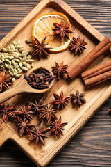 Board with anise stars, cinnamon, cloves and slice of dried orange on wooden background