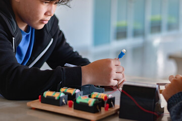 Children are studying electrical circuit systems by experimenting with electrical connections using...