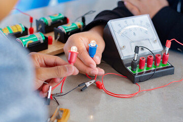 Children are studying electrical circuit systems by experimenting with electrical connections using...