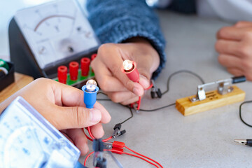 Children are studying electrical circuit systems by experimenting with electrical connections using...