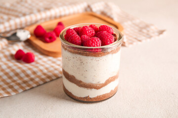 Glass with delicious raspberry cheesecake on beige background