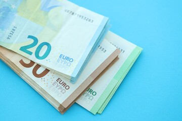Big amount of one hundred, twenty and fifty euro money bills on blue background