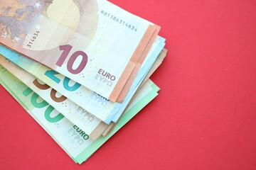 Big amount of one hundred, twenty, ten and fifty euro money bills on red background