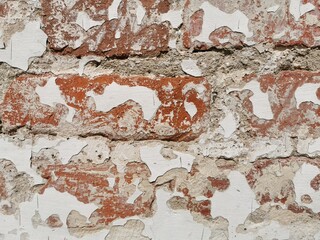 Detailed close-up background of weathered brick wall with peeling paint and exposed texture in a historic setting
