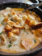 Delicious bowl of lohikeitto soup with bread croutons, close up view. Traditional Karelian and Finnish fish soup