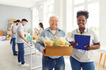 Portrait of friendly young African American volunteer girl with happy needy old aged man holding...