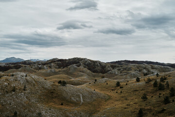 Mountain landscape in Durmitor National Park, Montenegro country in autumn season on cloudy day. Endless fields with dry yellow grass in the valley.