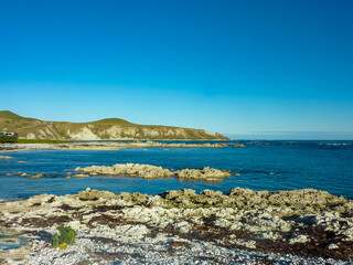 Rugged, rocky coastline meets calm, blue waters of Pacific ocean along Kaikoura Coast Track,...