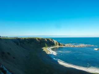 Dramatic coastal cliffs overlook rugged, rocky shore and vast expanse of Pacific ocean along...