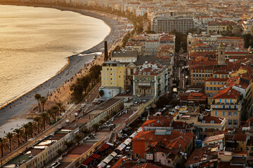 Obraz premium A picturesque aerial view of Nice, France, showcasing the Promenade des Anglais, palm-lined beach, vibrant architecture, and warm sunset light illuminating the city's charm
