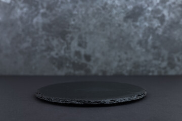 Round rustic black slate stone plate, on stone background