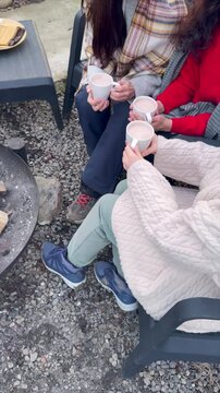 Friends enjoy warm drinks together outdoors during chilly afternoon gathering