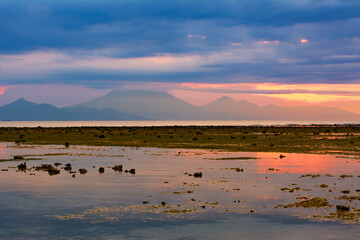 View of low tide of the Indian ocean and the outline of the island Bali and mount and volcano Gunung Agung from the beach of Gili Trawangan, Indonesia. Seascape at sunset. Reflection in water. 