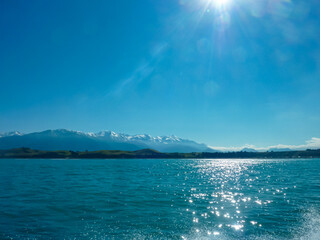 Majestic Seaward Kaikoura mountain range, seen from sea, Canterbury, New Zealand. Snow-capped peaks rise above veil of clouds, with tranquil waters of Pacific Ocean. Wilderness of coastal landscape