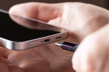 Close up of connecting usb c cable to the port of the modern phone. Charging modern phone