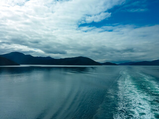 Untamed beauty of sea-drowned valleys Marlborough Sounds seen from Cook Straitn New Zealand. Forested hills meet vast Pacific Ocean under dramatic cloudy sky. Ferry trip between Picton and Wellington