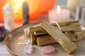 Palo santo sticks, gemstones and burning candles on white wooden table, closeup