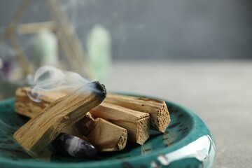 Smoldering palo santo stick and gemstone on table, closeup