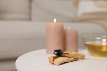 Palo santo sticks, burning candles and tea on white table indoors, space for text