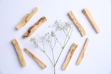 Palo santo sticks and gypsophila flowers on white background, flat lay