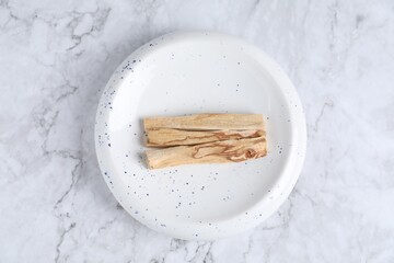 Palo santo sticks on white marble table, top view