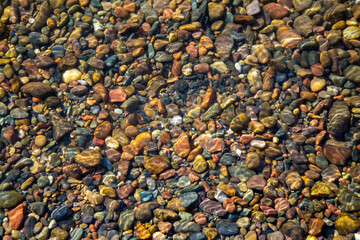 Stones on the river bottom under a layer of clean river water. Pebble texture. Ecology.