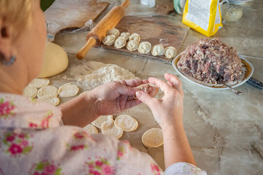 authentic photo of dumpling making at home. There is a dough on the table, flour and ground beef with onion for dumplings. High quality photo