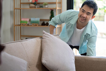 Obraz premium Gay couple relocating to their new home, one partner arranging furniture with a smile