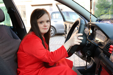 Naklejka premium A girl with Down syndrome driving a car. Accessibility and inclusiveness.