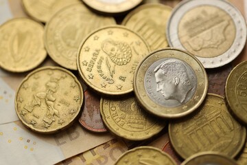 Many cent coins of euro currency lies on many fifty euro bills banknotes