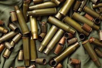 Many used rifle cartridges on military camo green fabric background