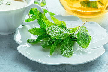 Mint tea. Fresh peppermint leaves with a cup and a tea pot in the background