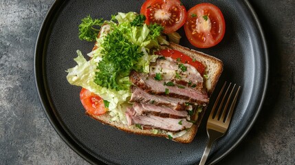 Gourmet sandwich featuring thinly sliced meat, fresh tomatoes, and shredded lettuce on a grey plate with vibrant parsley and a metallic fork.