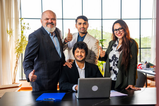 Group of Indian professionals in executive attire celebrate teamwork success with high five