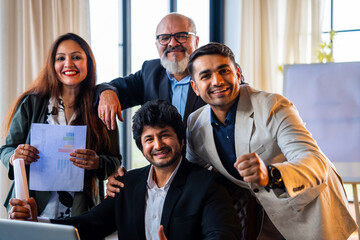 Group of Indian professionals in executive attire celebrate teamwork success with high five