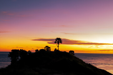 Fototapeta premium Background of young couples or solo travelers watching the natural light of the sunset at the Phuket seaside, Promthep Cape, a famous viewpoint that travelers from all over the world always visit.