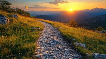 Scenic sunset view over a mountain trail with vibrant grass and distant peaks under a colorful sky