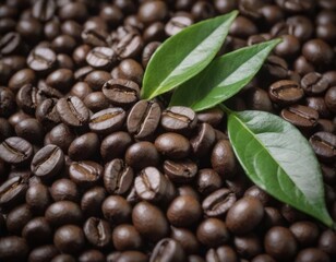 A mound of roasted coffee beans with green leaves on top