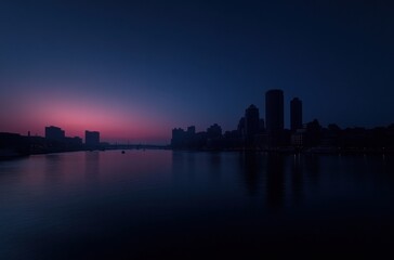 Fototapeta premium Serene Urban Skyline at Dusk with Reflections on Water and City Lights in the Background, Capturing the Tranquility of Evening in a Metropolis