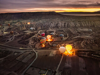 Aerial drone view of Göreme with lights on at dusk during sunrise, with hot air balloons preparing...