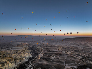  Hundreds of hot air balloons above Love Valley with tall chimney-like rock formations in Cappadocia at sunrise