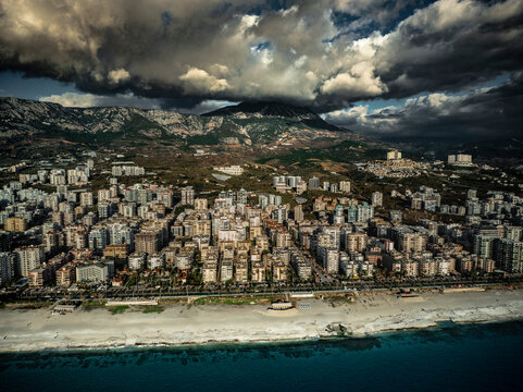 Aerial view of Mahmutlar district in Alanya with numerous high rise buildings by the sea and a mountain shrouded in clouds in the background