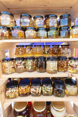 Jars of honey with various nut fillings stand on the shelf. Honey products.